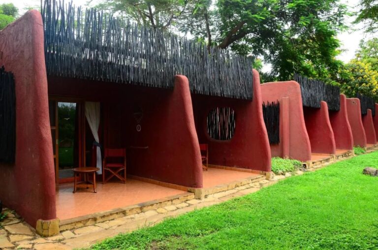 Le terrazze delle camere dell'Amboseli Serena Safari Lodge, tra muri rossi arrotondati, davanti a un prato