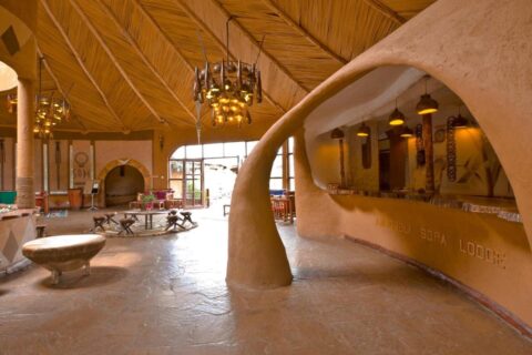 Il bancone in terra scolpita della reception, inciso con il nome dell'Amboseli Sopa Lodge, sotto un soffitto di canne