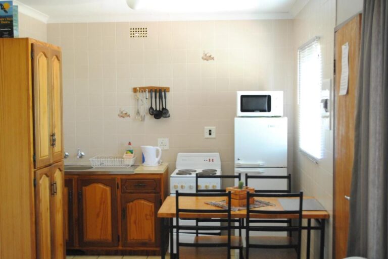 Una cucina attrezzata con piastre elettriche, frigorifero, microonde e bollitore, e un tavolo per quattro