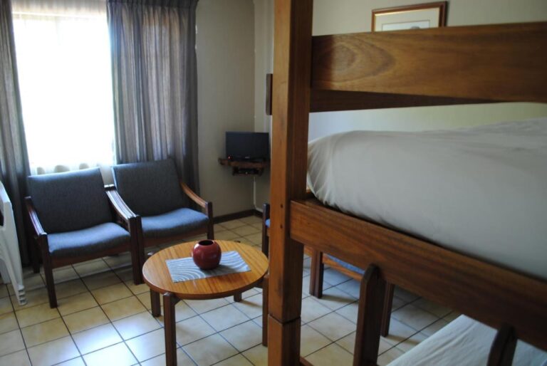 Due poltrone blu e un tavolino rotondo, accanto a un letto a castello in legno, su un pavimento piastrellato