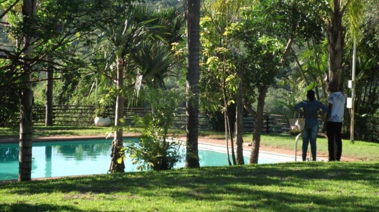 La piscina degli Eagles Nest Chalets in mezzo al prato e agli alberi, con due persone in piedi sul bordo