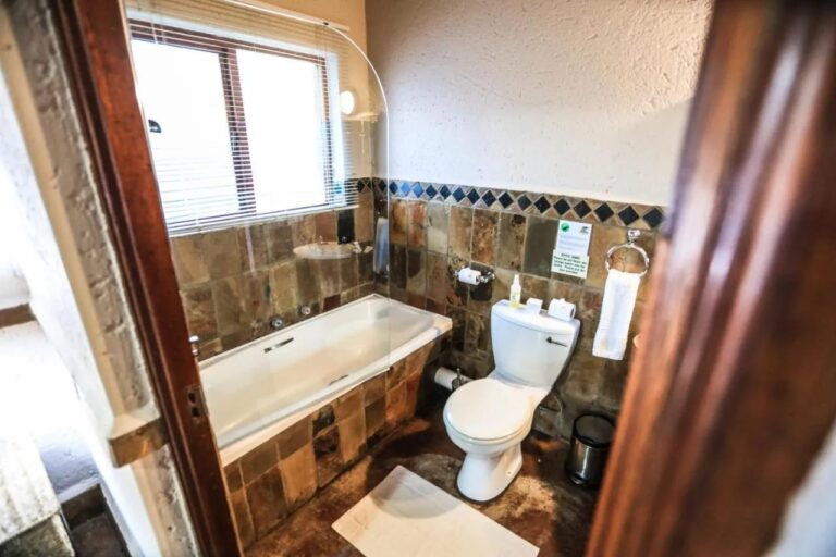 Un bagno con vasca e WC, con le pareti rivestite in pietra