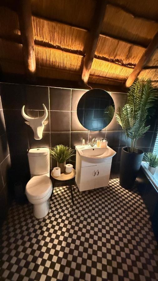Un bagno con il pavimento a scacchi bianchi e neri, uno specchio rotondo e una testa di toro bianca alla parete