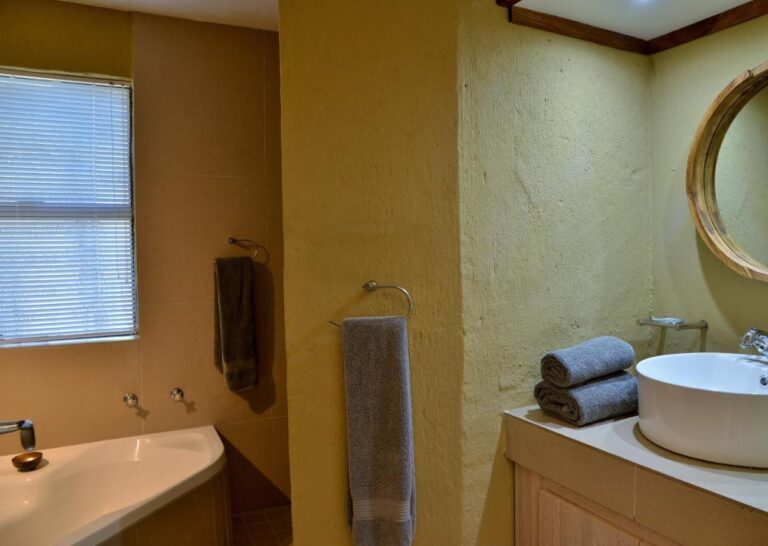 Un bagno con vasca, lavabo rotondo da appoggio e specchio rotondo con cornice in legno