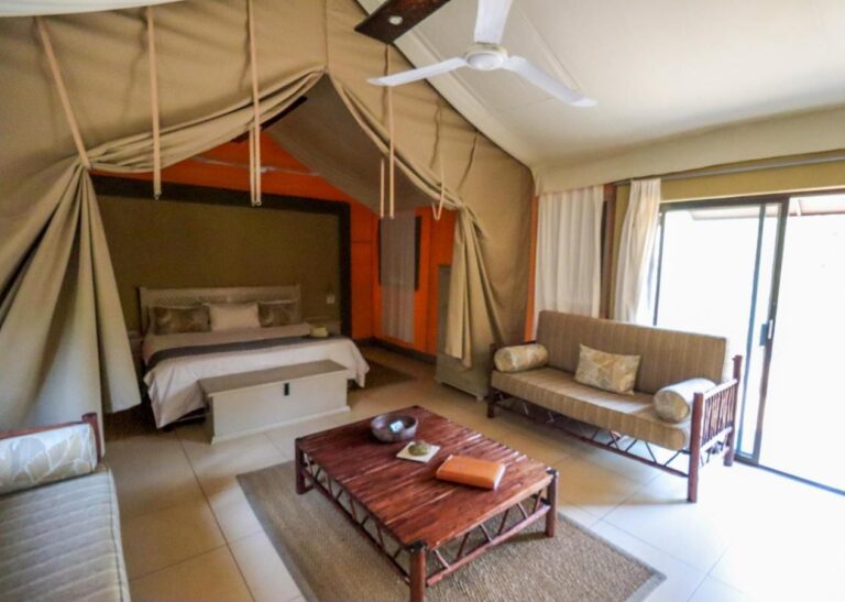 L'interno di una tenda, con un letto matrimoniale, un divano, un tavolino in legno e una grande vetrata