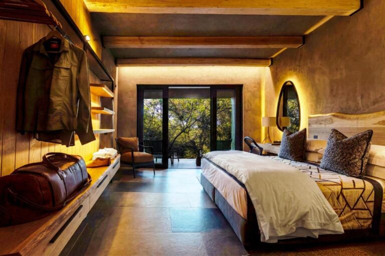 Una suite con un grande letto, aperta su una terrazza tra gli alberi