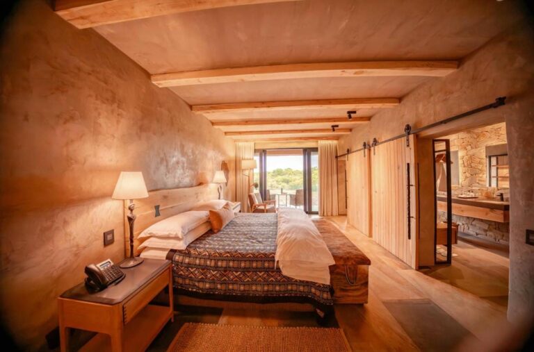 Una suite vista in lunghezza, dal letto alla terrazza, con il bagno dietro una porta scorrevole