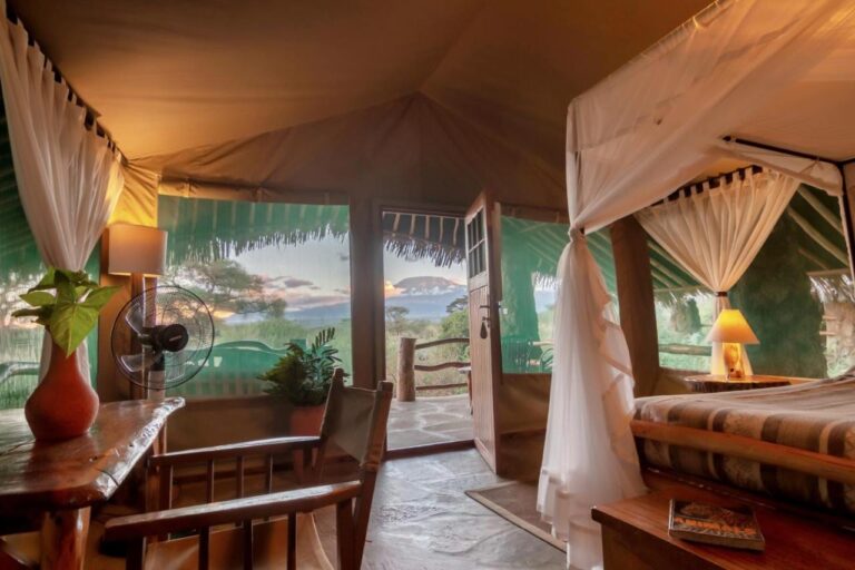 Una tenda del Kibo Safari Camp aperta sulla terrazza, con il Kilimangiaro in lontananza al crepuscolo