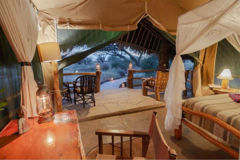 La scrivania di una tenda con una lanterna, davanti alla terrazza coperta di paglia e alla boscaglia