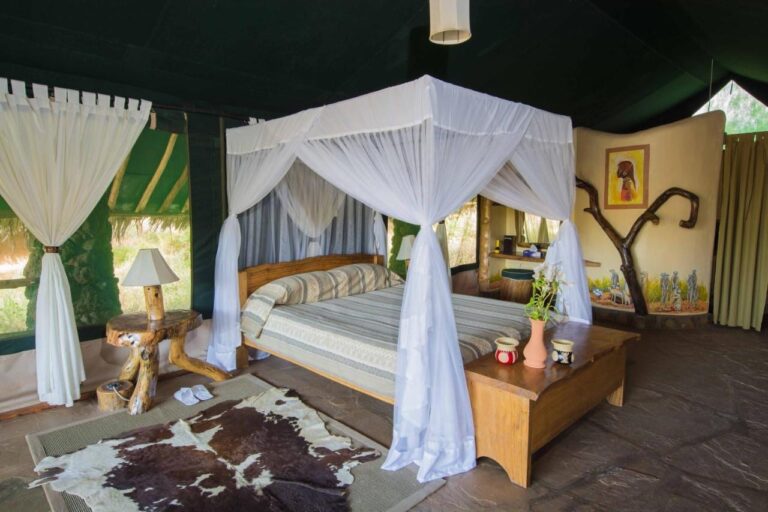 Una tenda dalle pareti verde scuro, con un letto con zanzariera, un baule e una pelle di mucca sul pavimento