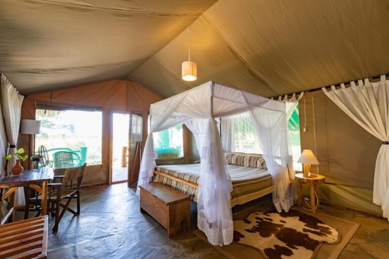 Una tenda con un letto con zanzariera, una scrivania e una porta aperta sulla terrazza