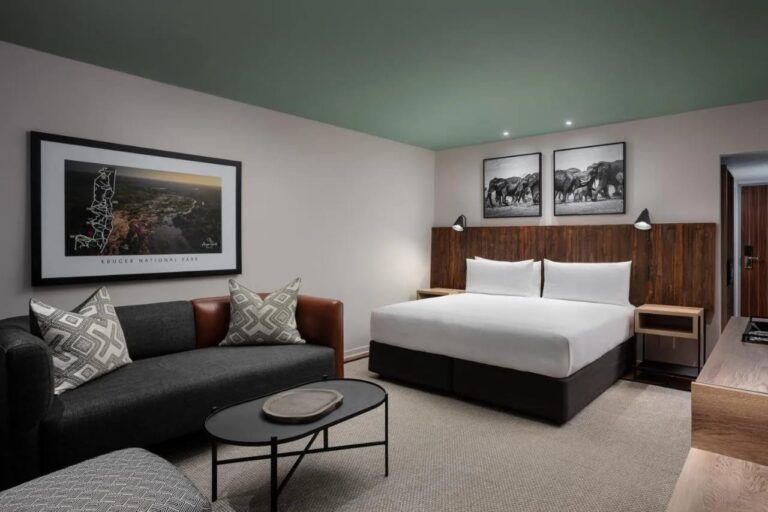 Una camera Deluxe con un letto matrimoniale e un divano, al Kruger Gate Hotel