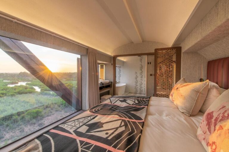 L'interno di un vagone del Kruger Shalati, con il letto davanti a una grande finestra sul fiume e la vasca sul fondo