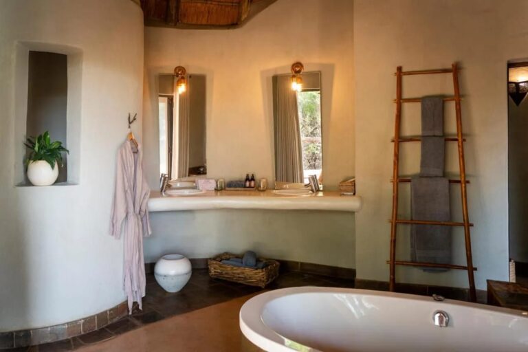 Un bagno con le pareti curve, una vasca, due lavabi e un portasciugamani a scala