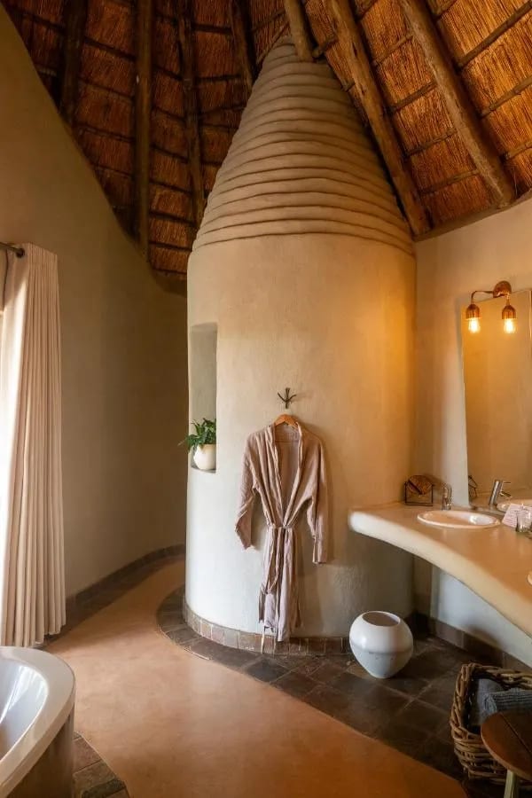 Un accappatoio appeso a una torretta curva, in un bagno sotto il tetto di paglia