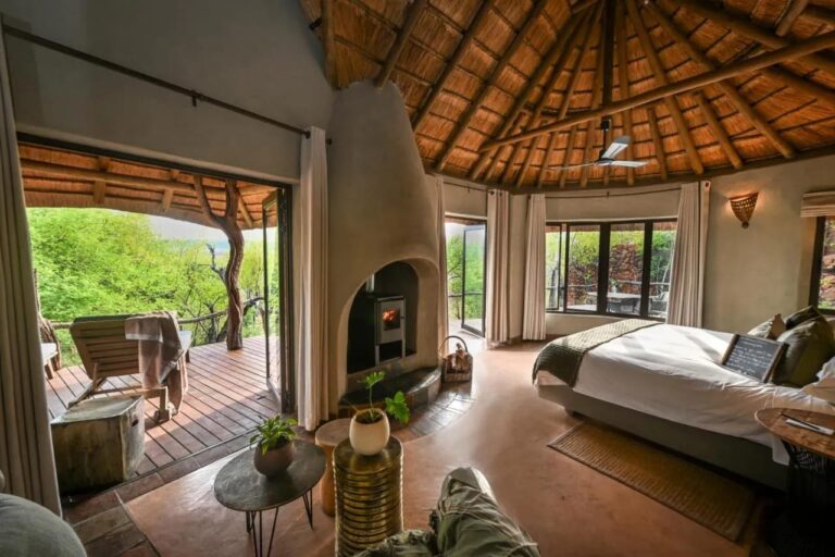Una suite aperta su una terrazza davanti agli alberi, con una stufa a legna e un grande letto