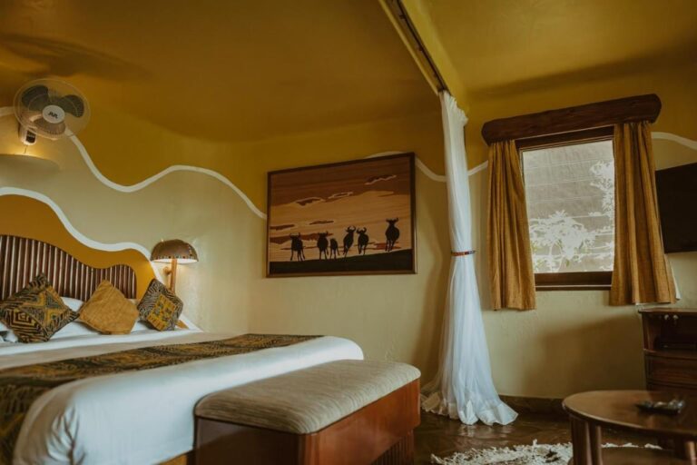 Una camera con un quadro di gnu in silhouette sopra il letto e un ventilatore a parete