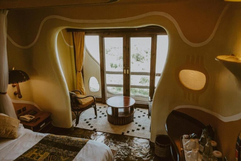Una camera dalle pareti curve del Mara Serena Safari Lodge, con un angolo salotto davanti alla porta-finestra del balcone