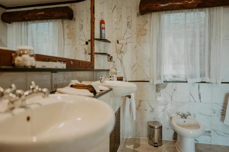 Un lavabo in primo piano in un bagno di marmo, con un bidet sul fondo