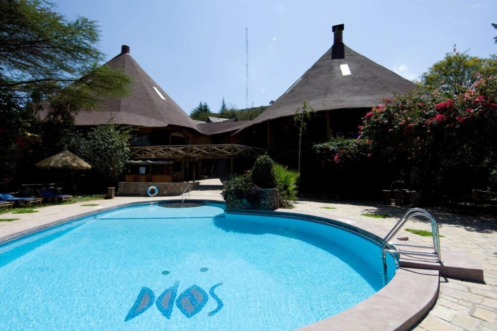 La piscina del Mara Sopa Lodge, davanti a edifici con grandi tetti conici di paglia