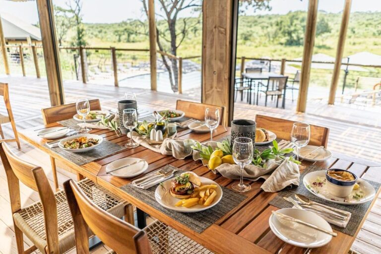 Un tavolo apparecchiato al ristorante, aperto sulla terrazza, sulla piscina e sulla boscaglia