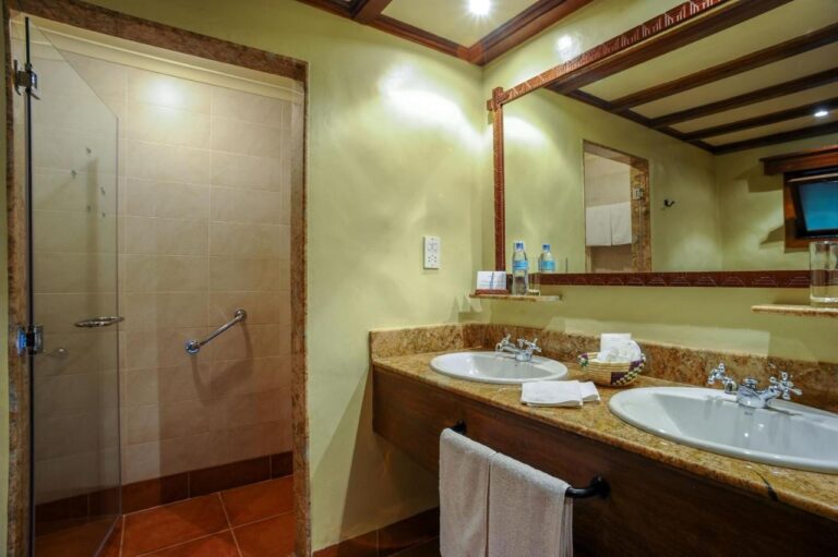 Un bagno con due lavabi e una doccia in vetro