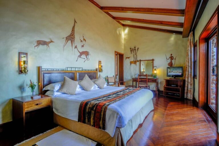Una camera con un letto matrimoniale, una scrivania, una TV e una giraffa dipinta sul muro
