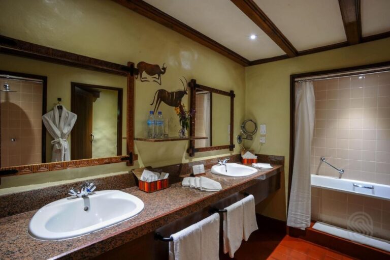 Un bagno con due lavabi, una vasca e un accappatoio appeso