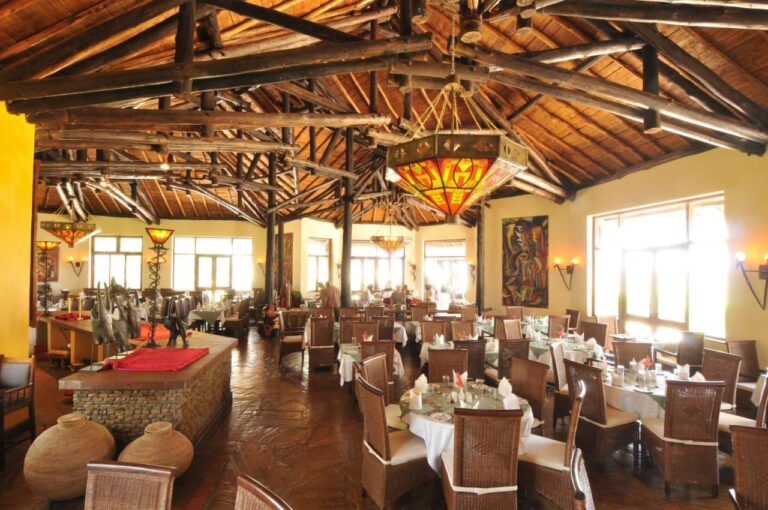 La sala del ristorante sotto una travatura di tronchi, con lampadari in vetro colorato e tavoli dalle tovaglie bianche