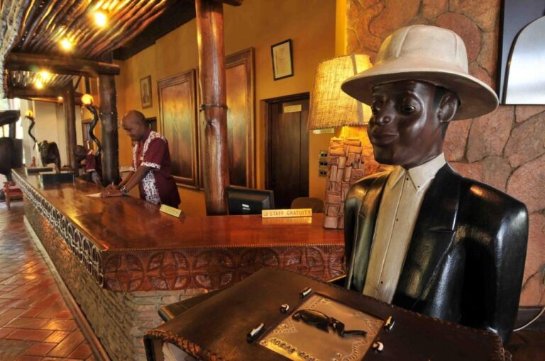 La reception, con un bancone scolpito e la statua in legno di un uomo con il casco coloniale