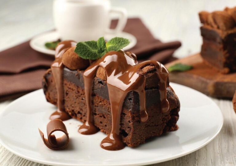 Una fetta di torta al cioccolato coperta di salsa, con foglie di menta