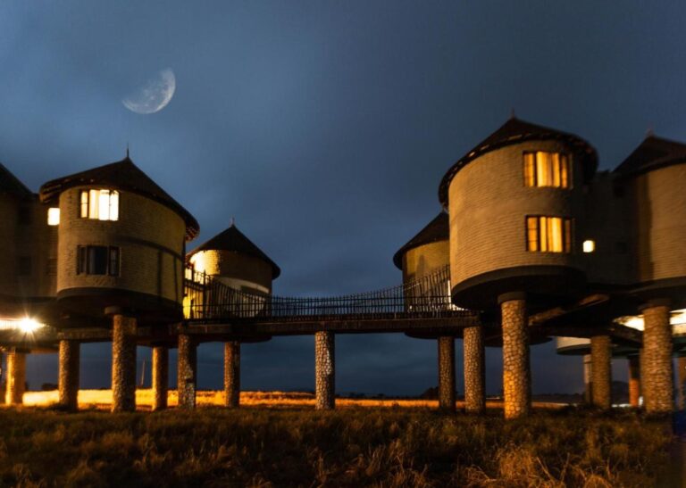 Due torri illuminate collegate da una passerella, sui loro pilastri di pietra, sotto la luna