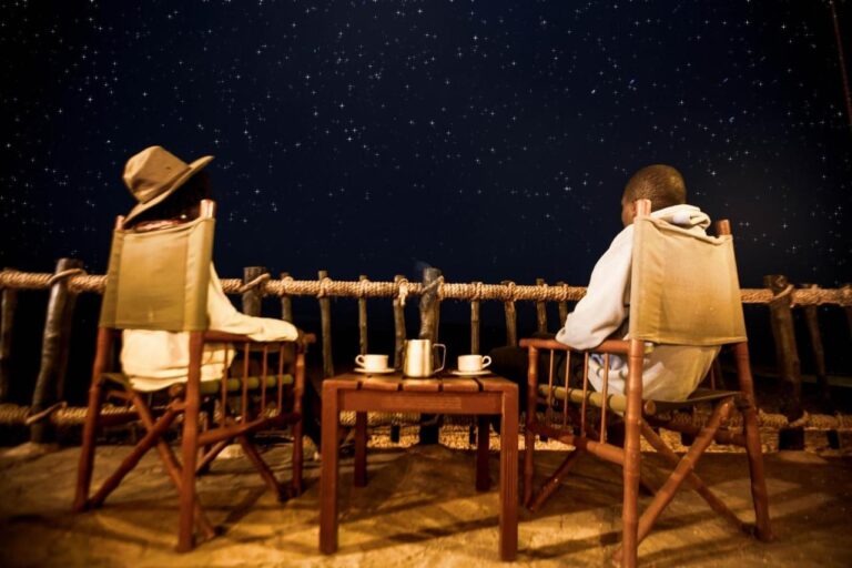 Due persone sedute su poltrone di tela sulla terrazza, con due tazze sul tavolo, sotto un cielo stellato