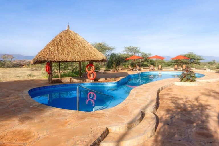 La piscina del Samburu Sopa Lodge, con il gazebo dai salvagenti arancioni e gli ombrelloni rossi davanti alla boscaglia