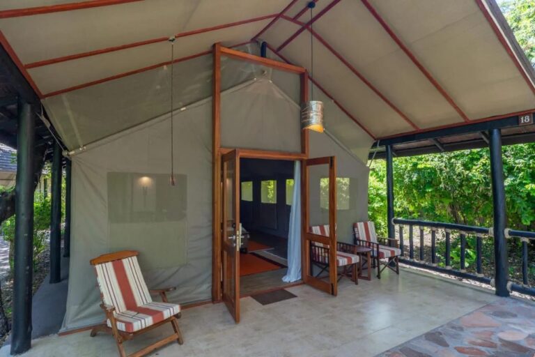 L'ingresso di una tenda riparata da un tetto, con sedie a righe sulla veranda