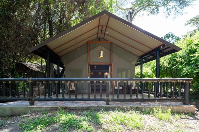 Una tenda del Sarova Mara Game Camp sotto il suo tetto, su una terrazza con balaustra, tra gli alberi