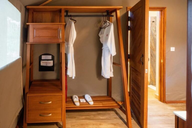 Un guardaroba aperto con due accappatoi e delle pantofole, vicino alla porta del bagno