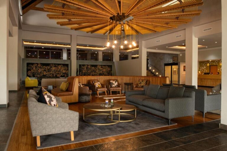 Il salotto della hall, con divani grigi e poltrone in pelle, sotto un soffitto di listelli di legno