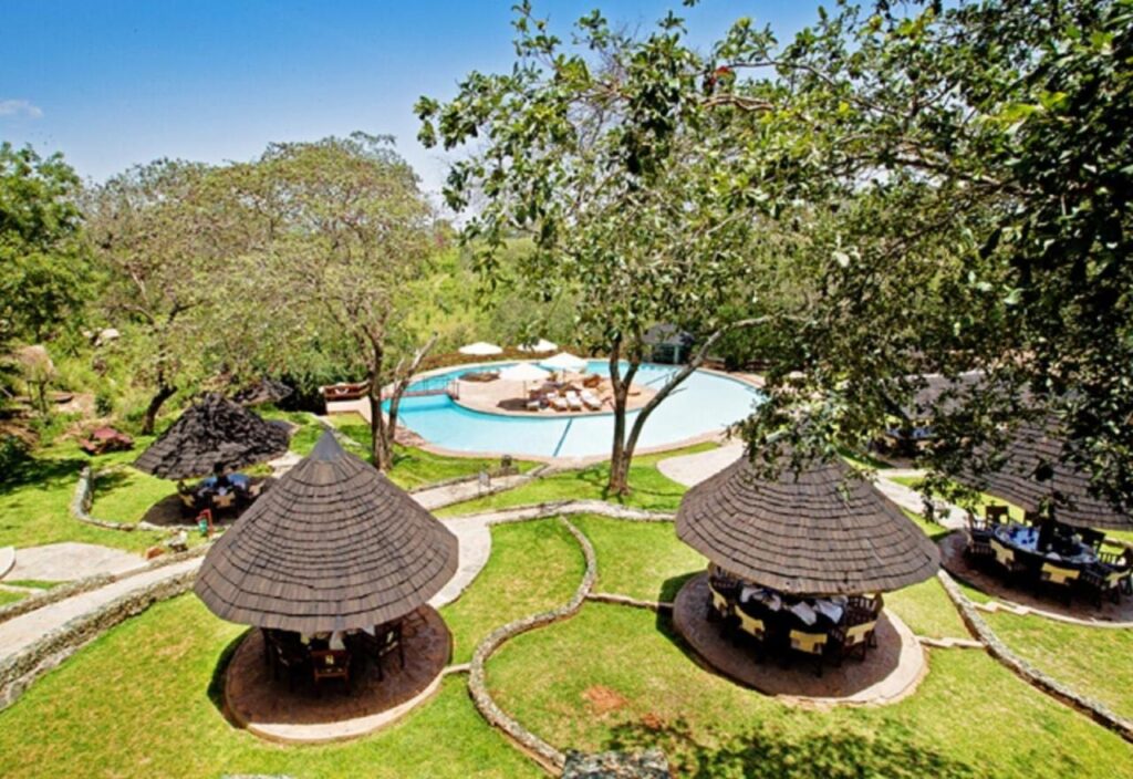 La piscina del Tarangire Sopa Lodge e i suoi gazebo con il tetto di paglia, in mezzo agli alberi