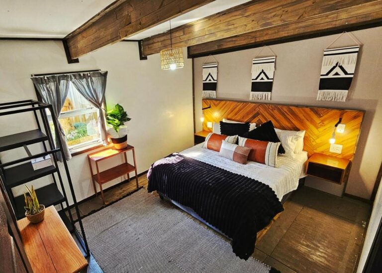 Una camera di The Elements con un letto matrimoniale, una testiera in legno a spina di pesce e tre teli decorativi in bianco e nero, sotto travi a vista