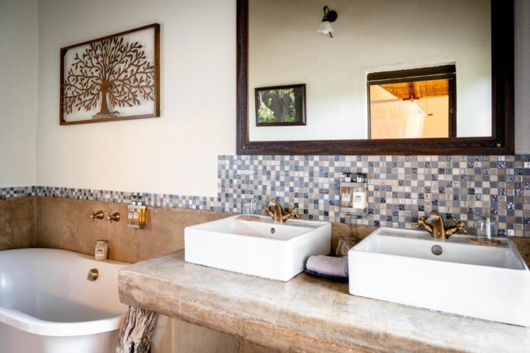 Un bagno con due lavabi su un piano in cemento, una vasca e un paraschizzi a mosaico