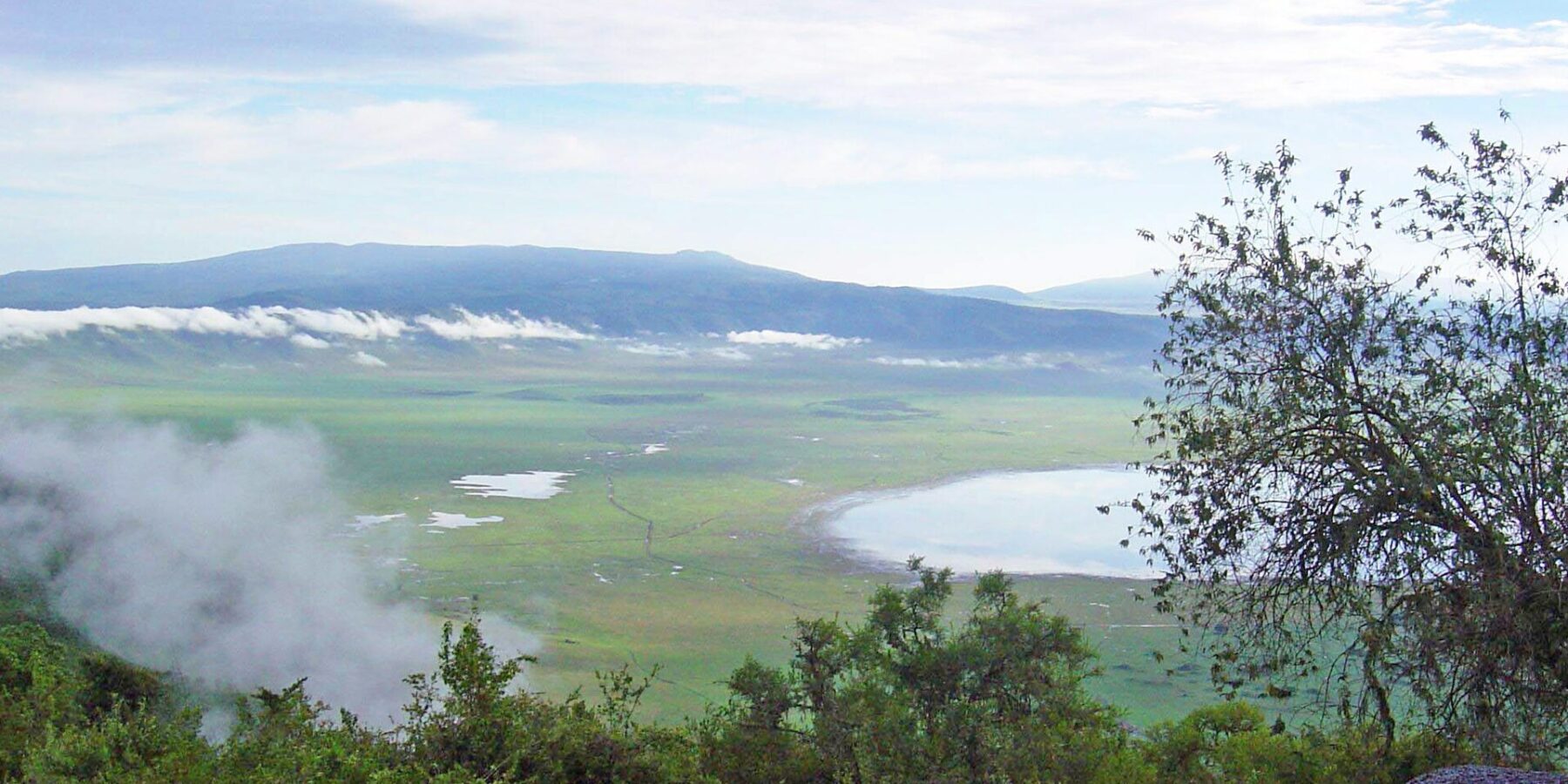 Il fondo verde del cratere visto dal bordo, con il lago Magadi e le nuvole aggrappate alle pareti